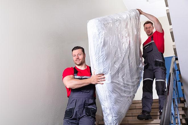 two workers lifting a box spring onto a truck in Wakefield